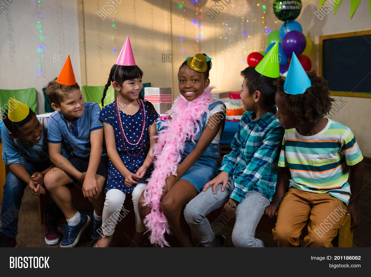 happy children sitting against wall during birthday party