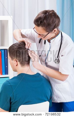 doctor inspecting skin of head