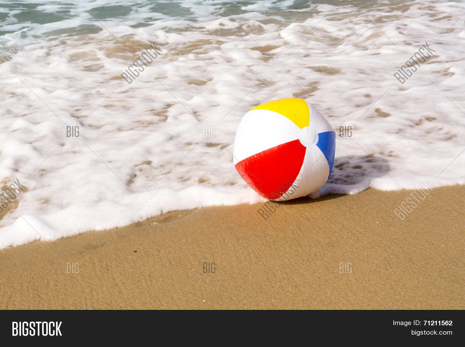a colorful, summertime beach ball washes up to a sandy beach