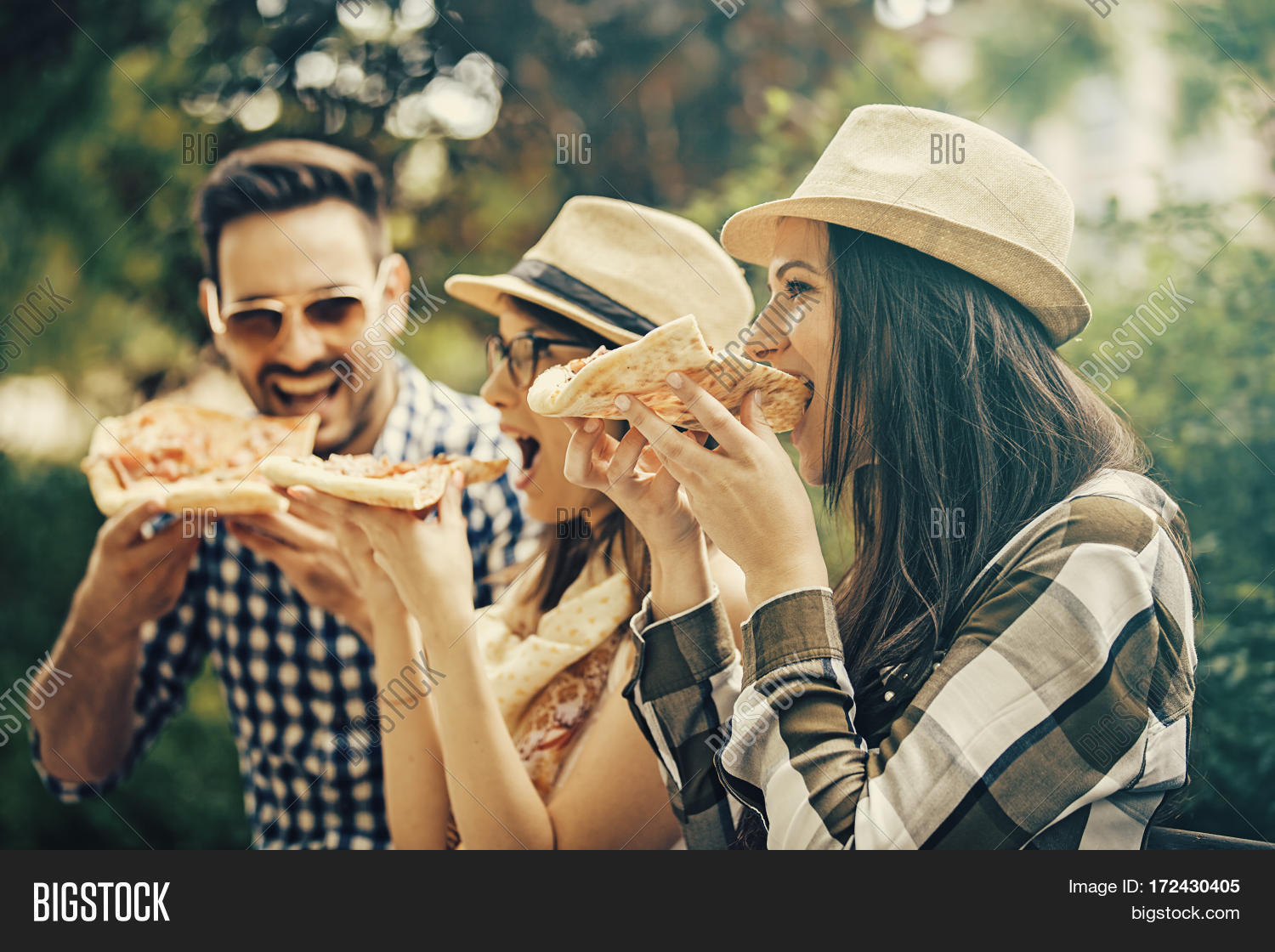 group of young people having fun in the park and eating pizza.