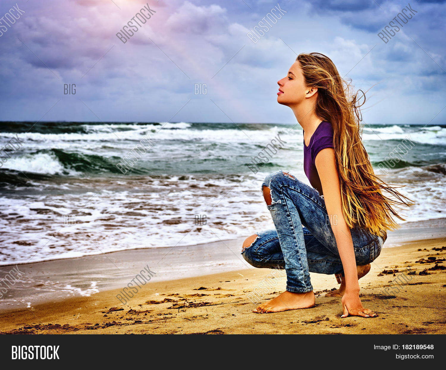 girl on in sand beach looks thoughtfully into distance to last