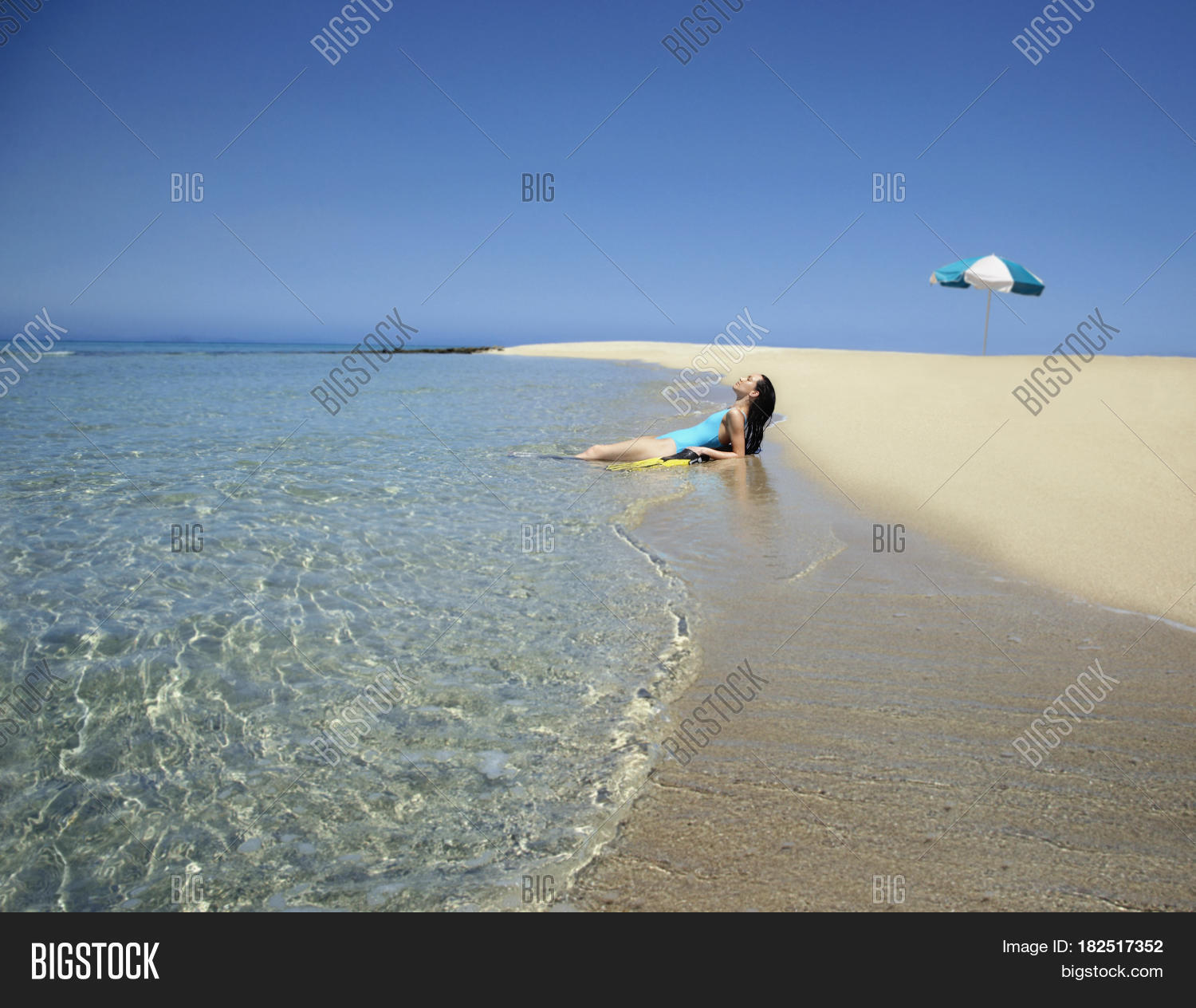 pacific islander woman laying in surf at beach