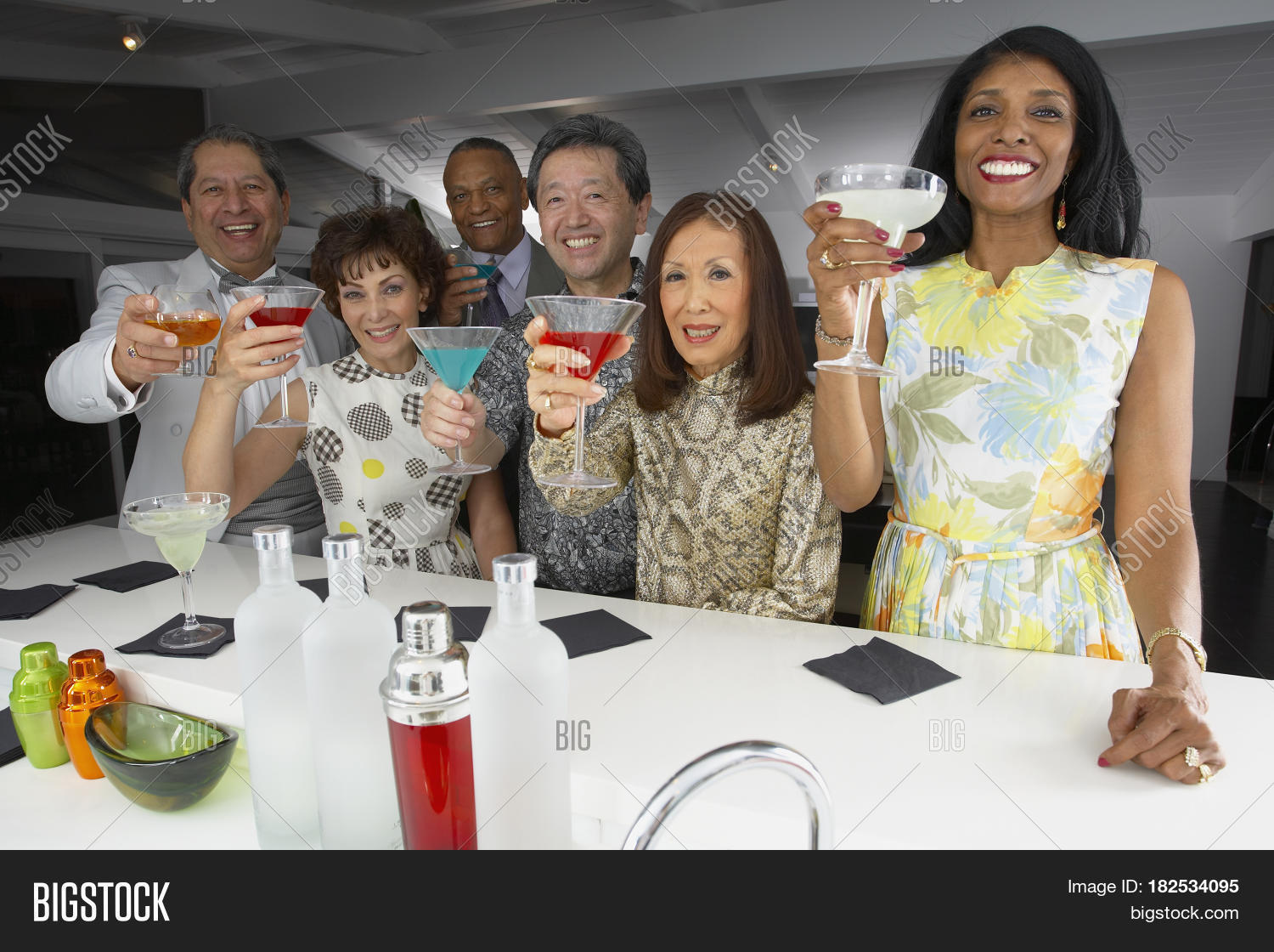 multi-ethnic group of friends drinking cocktails at party