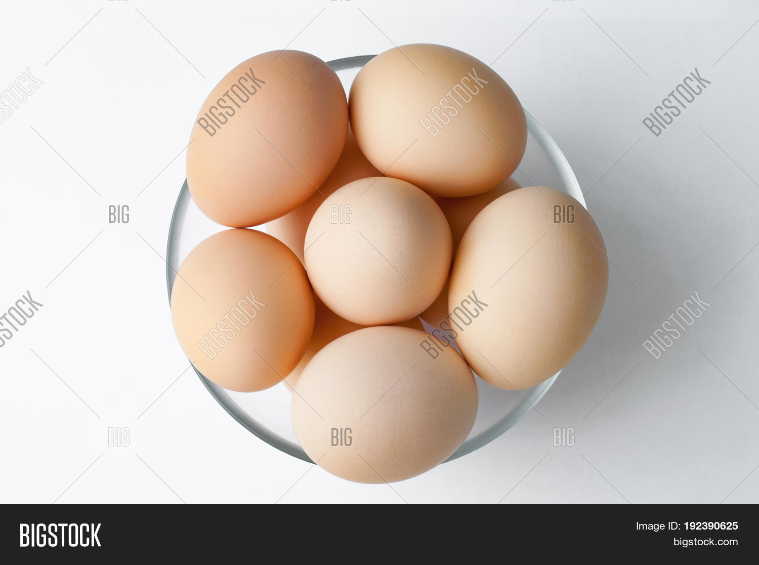 brown hen eggs in glass bowl on white table. fresh farmers egg.