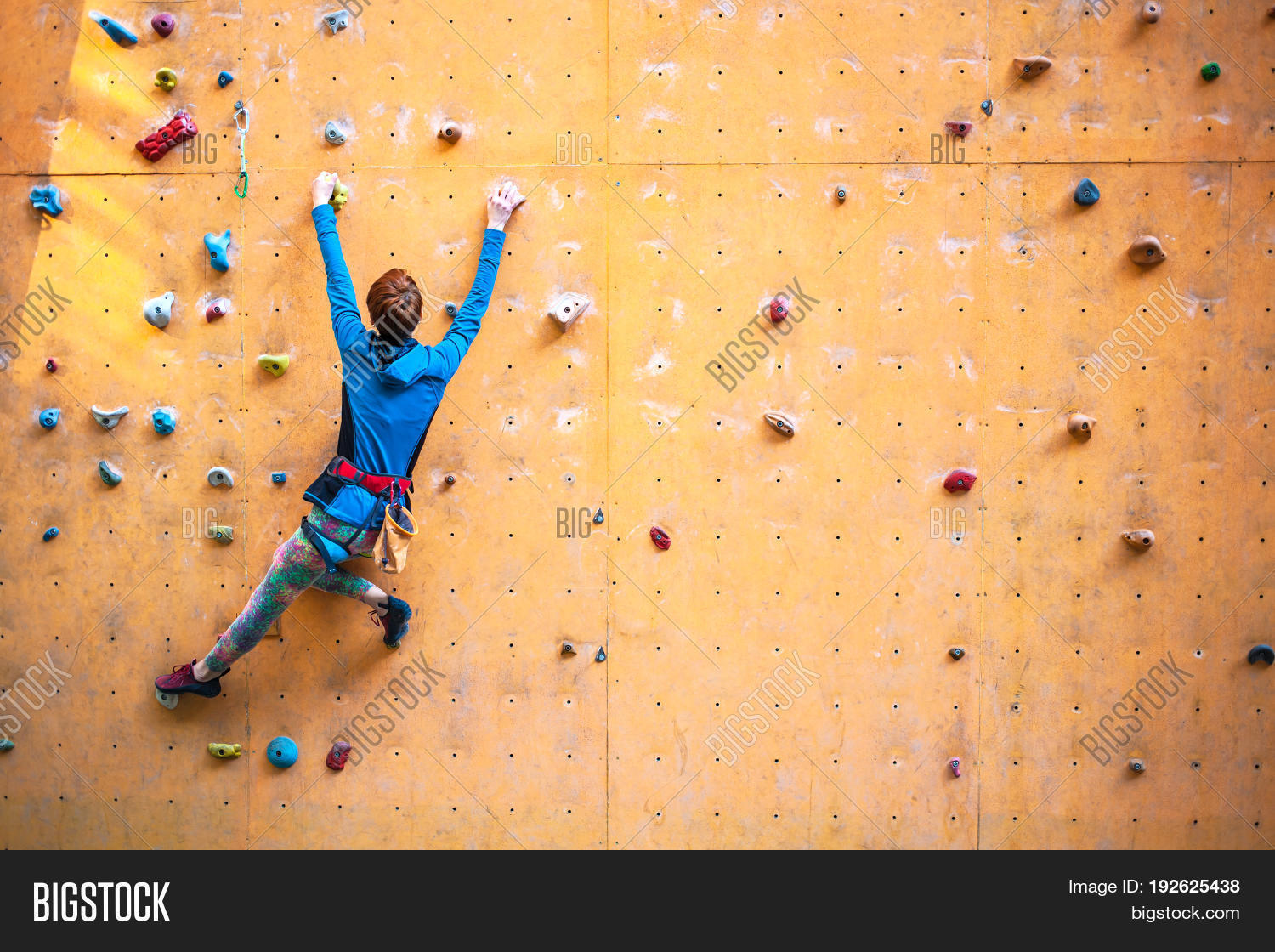 a young woman with short hair climbs on the climbing wall.