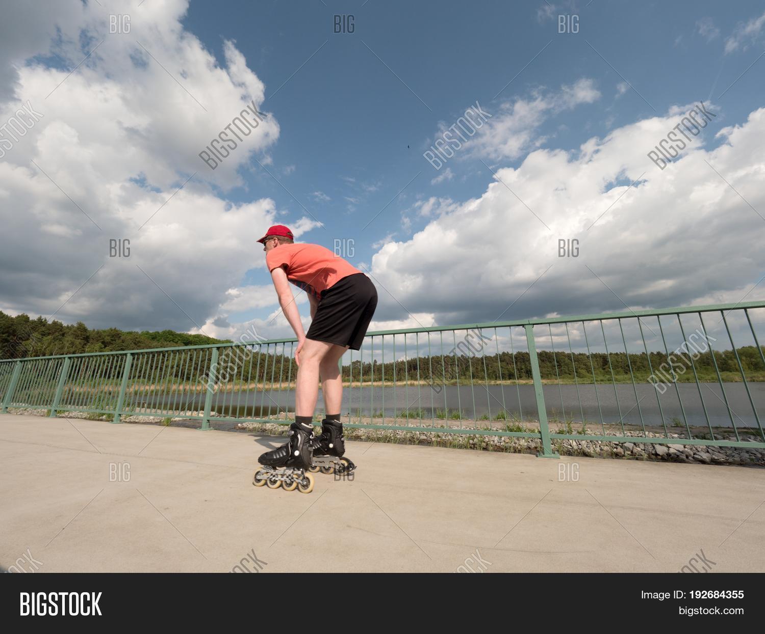 middle age man in red t-shirt with inline skates ride in summer