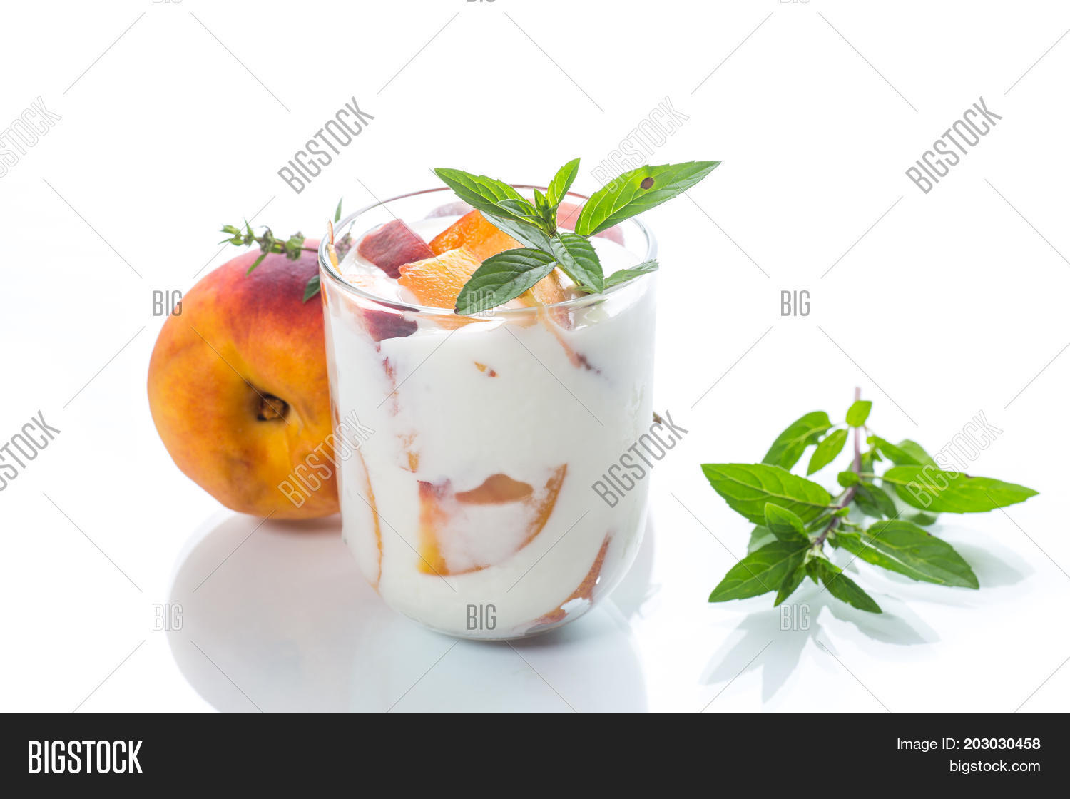 sweet home-made yogurt with pieces of peach in a glass cup