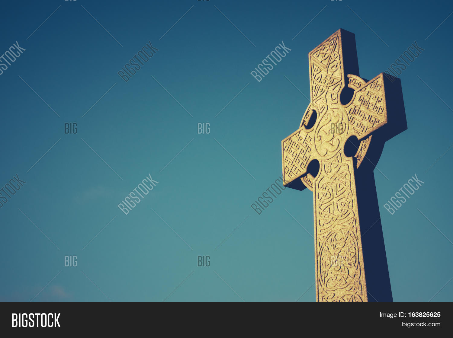 celtic cross stone gravestone against blue sky with copy space