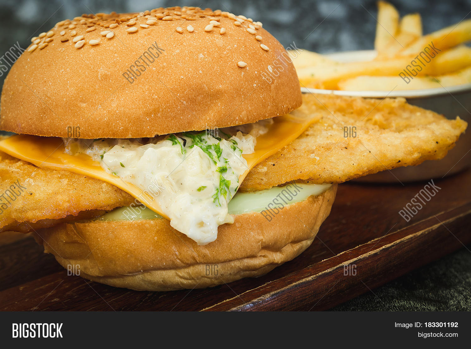 a fresh made fish burger on wooden plate (close-up shot
