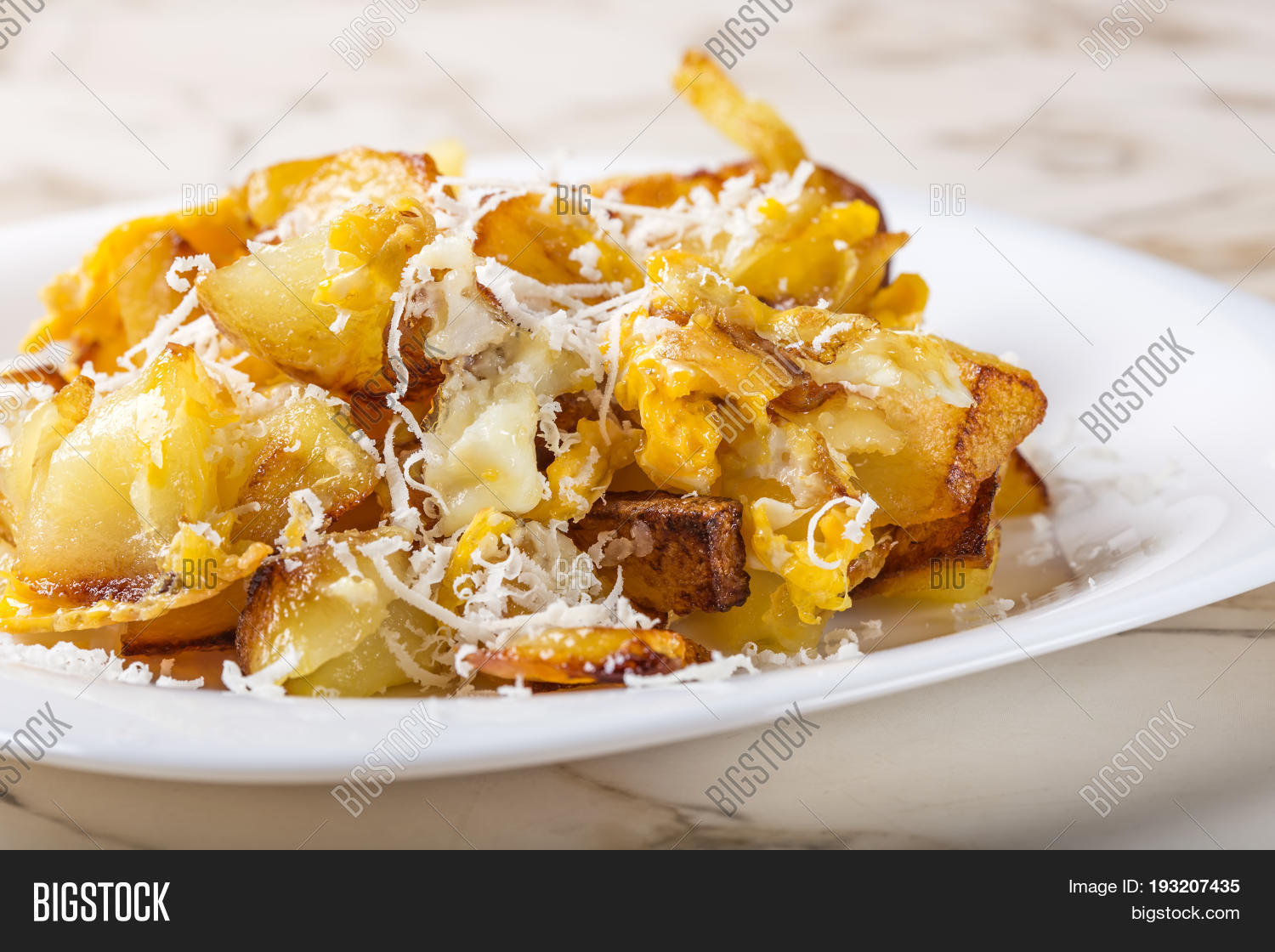 fried potatoes with scrambled eggs and parmesan cheese on white