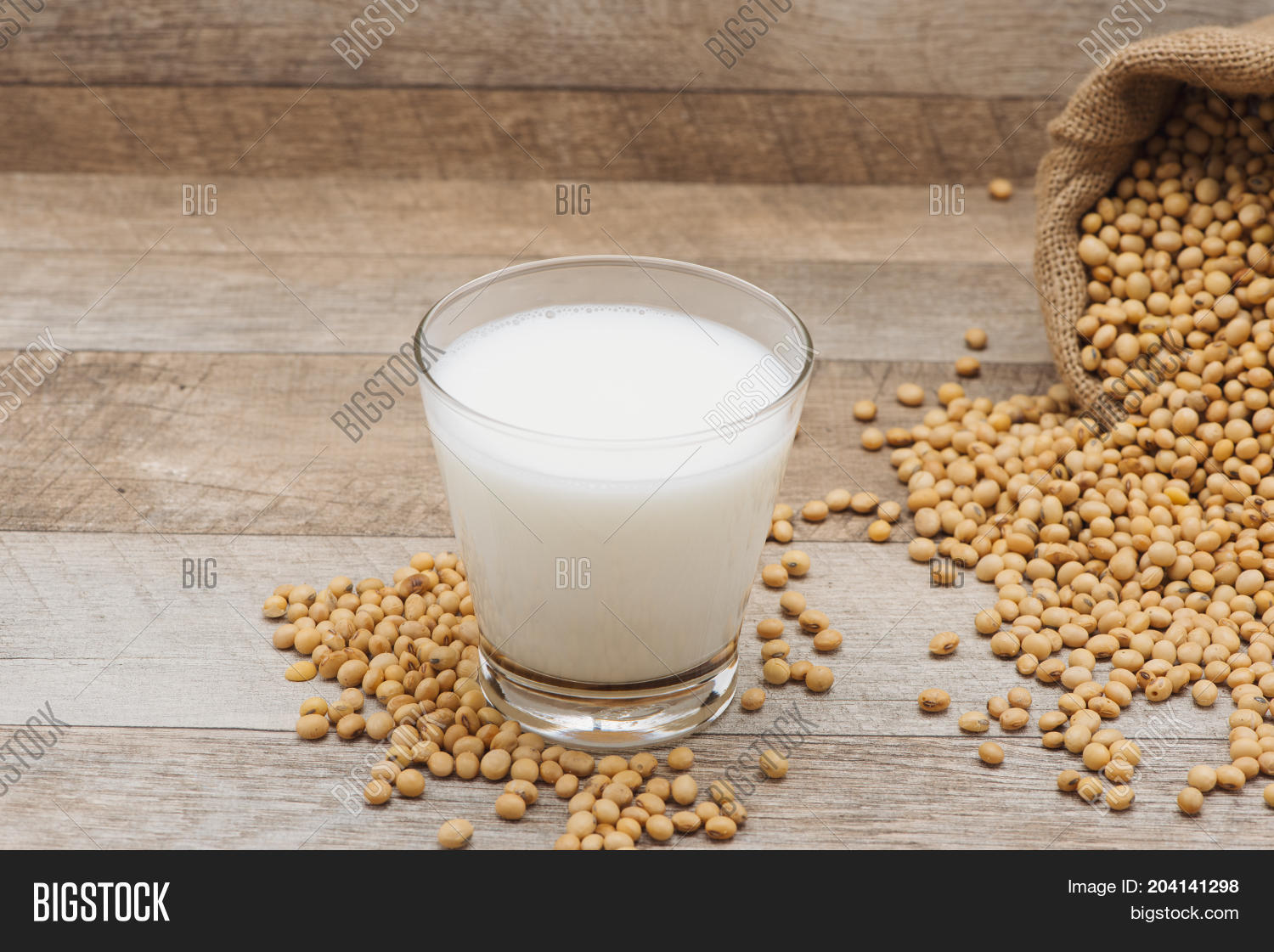 glass with soy milk and soy bean on wooden background