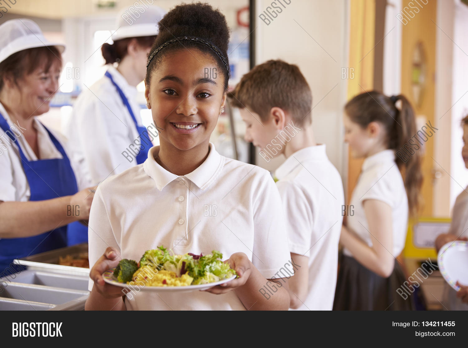 black schoolgirl holds a plate of food in a school cafeteria