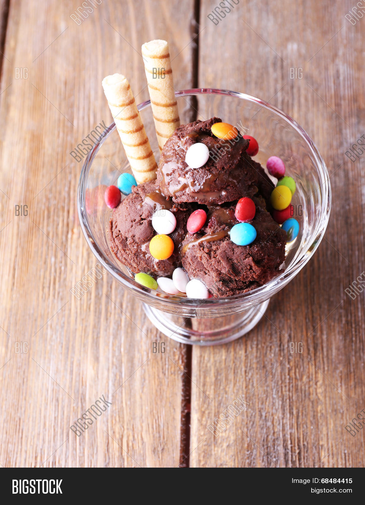 chocolate ice cream with multicolor candies and wafer rolls in