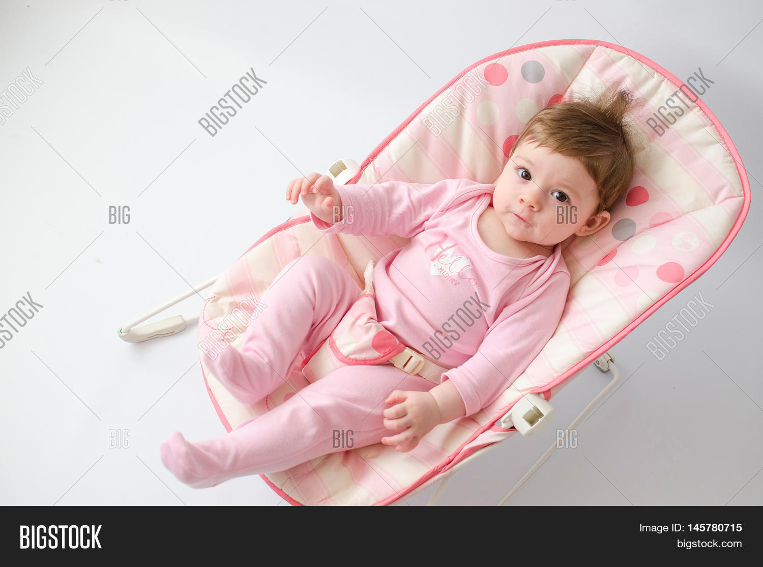 beautiful happy baby girl in a bouncer wearing pink onesie