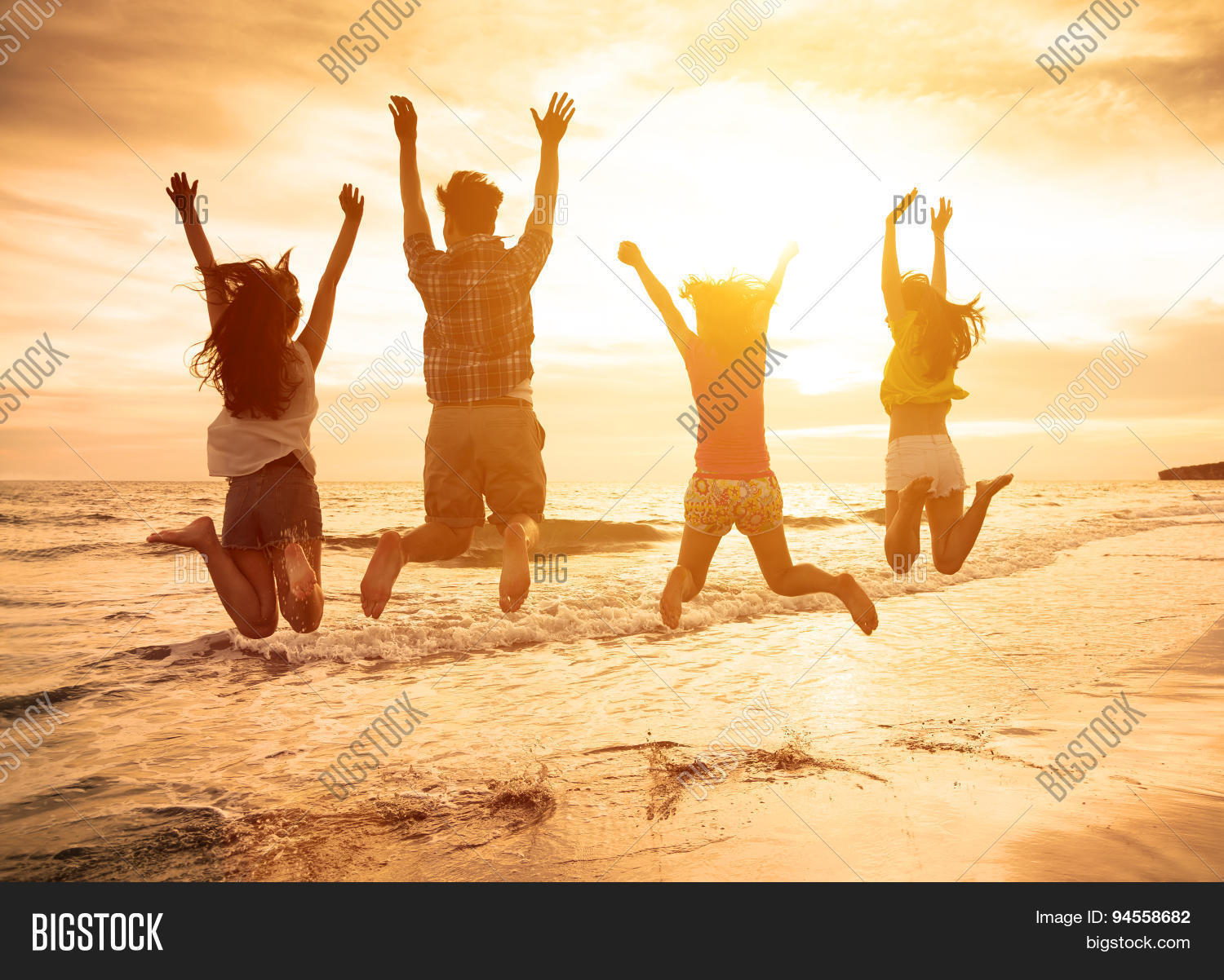 group of happy young people jumping on the beach