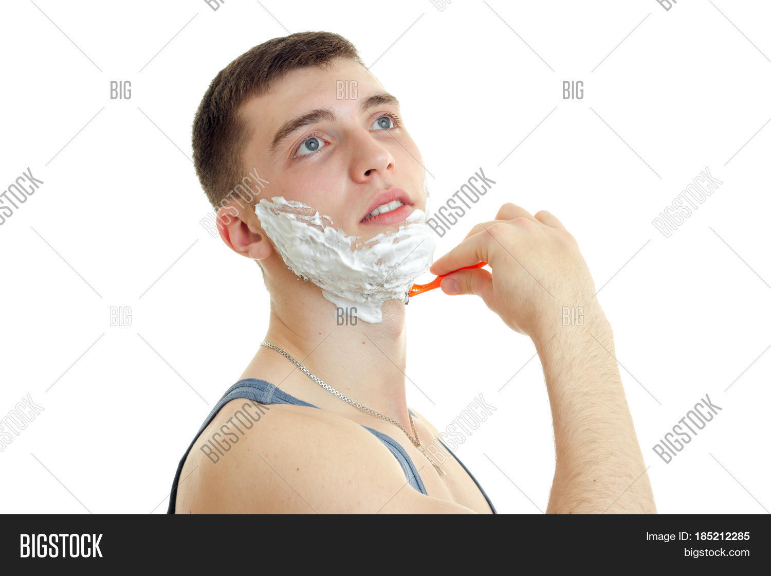 young guy raised his head up and shaves his beard foaming close