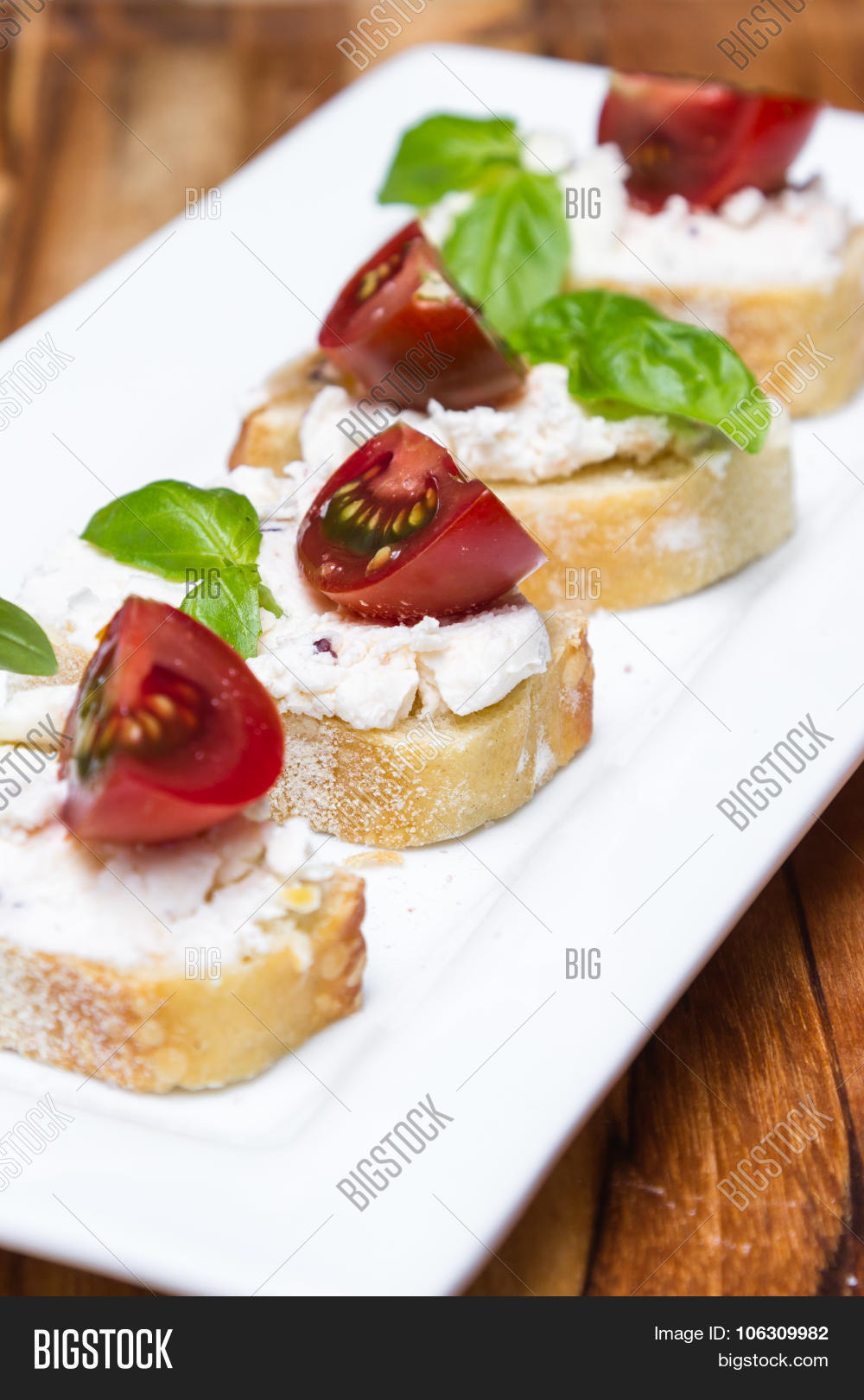 with goat cheese and tomato on a piece of bread garnished with