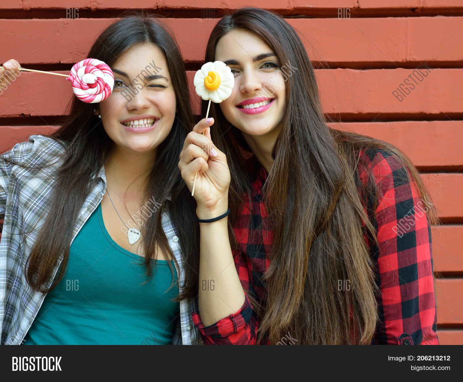 two beautiful girls have fun embracing with sweet candies out