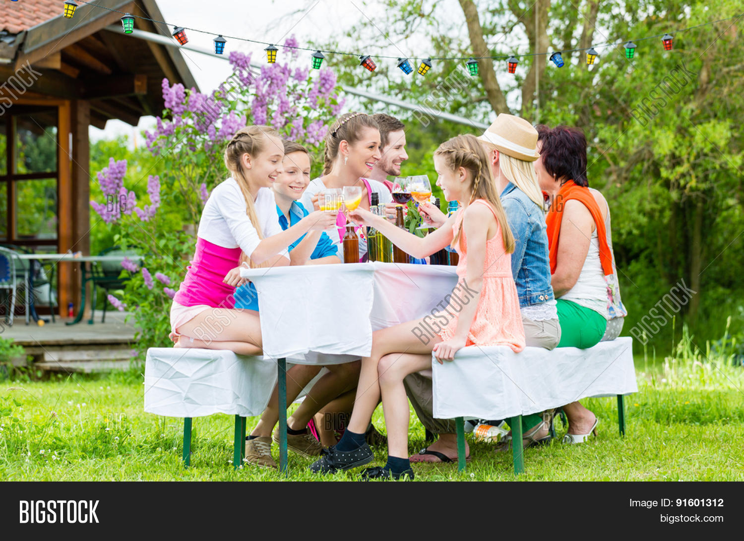 family and neighbors at garden party drinking, sitting in front
