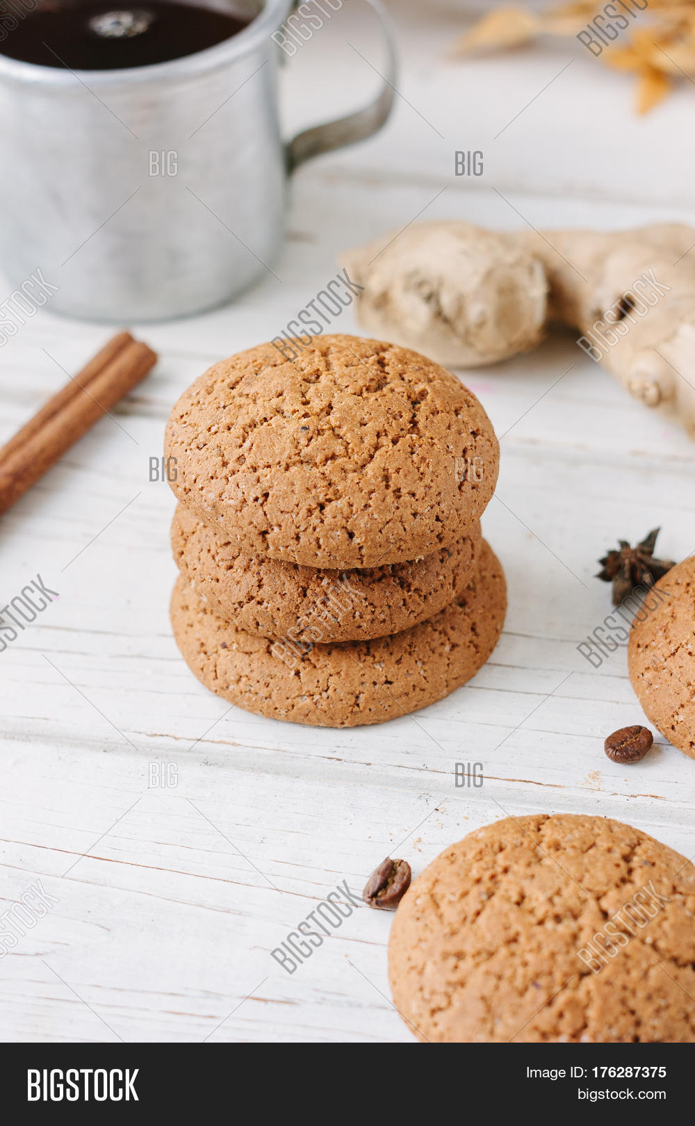 ginger snaps on white wooden surface with spices around.