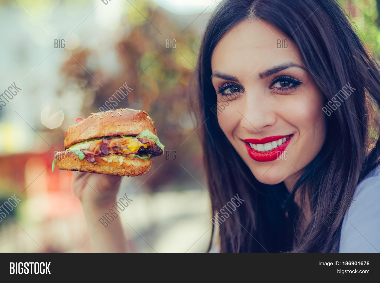 portrait of a young happy woman eating tasty fast food burger