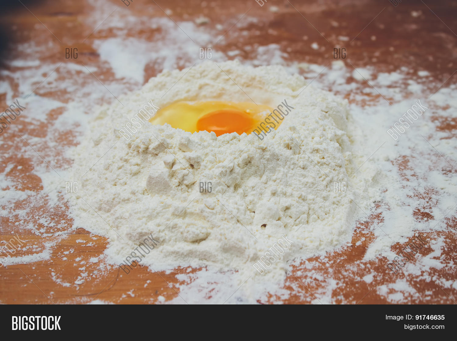 making bread mixing food ingredients: egg yolk on a flour staple