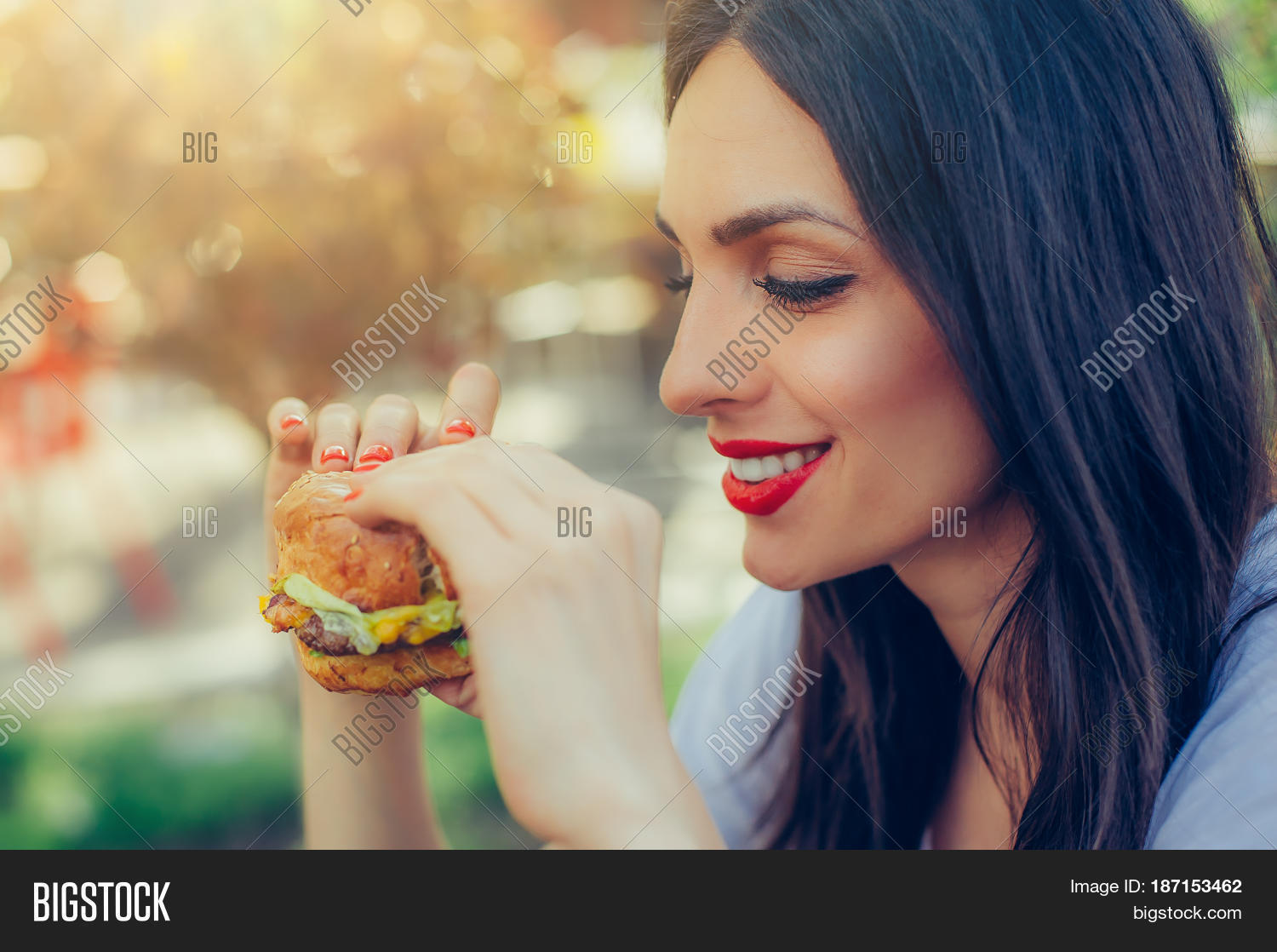 portrait of a young happy woman eating tasty fast food burger
