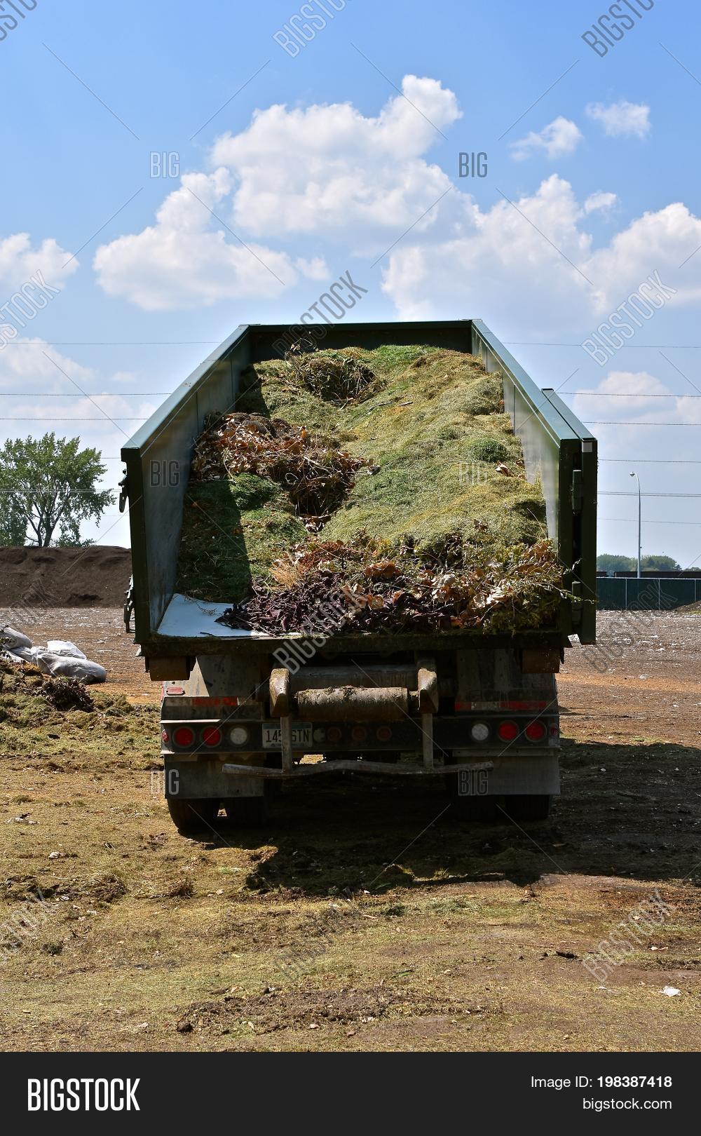 hydraulic lift on a truck box uses gravity to unload grass