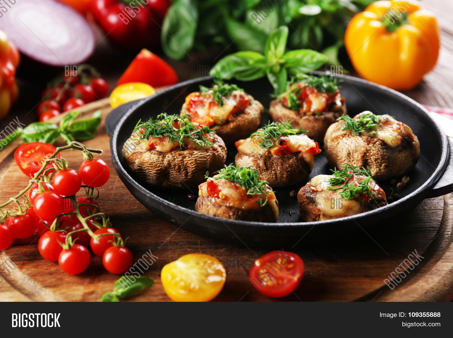 a frying pan with stuffed mushrooms and vegetables on the table