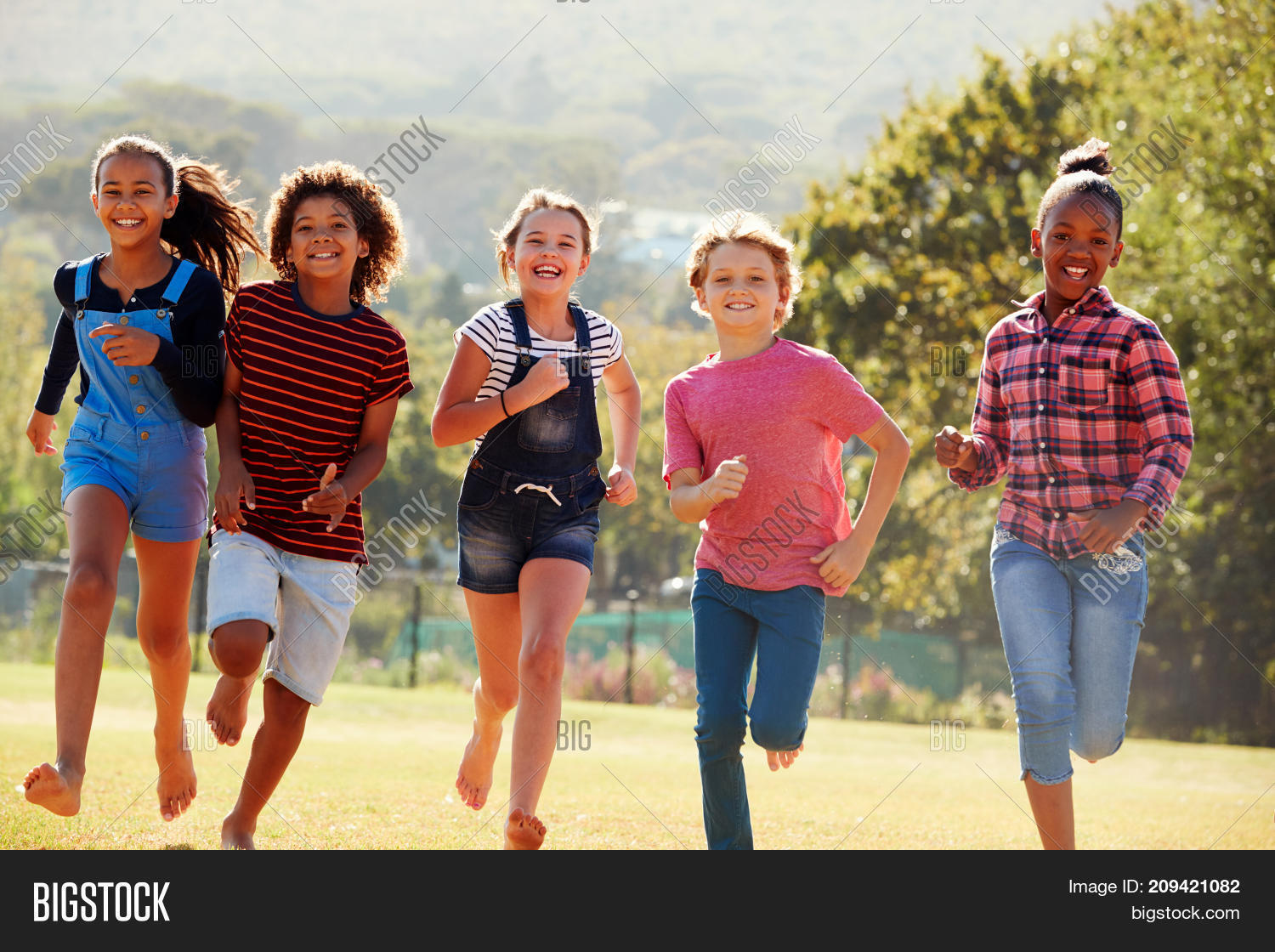 six pre-teen friends running in a park, front view, close up