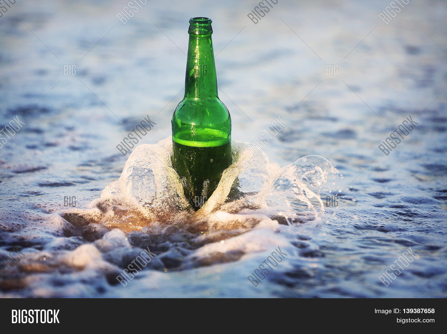 a bottle of beer on the beach. waves wash a beer bottle.