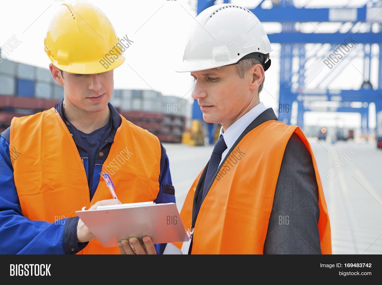 workers discussing over clipboard in shipping yard